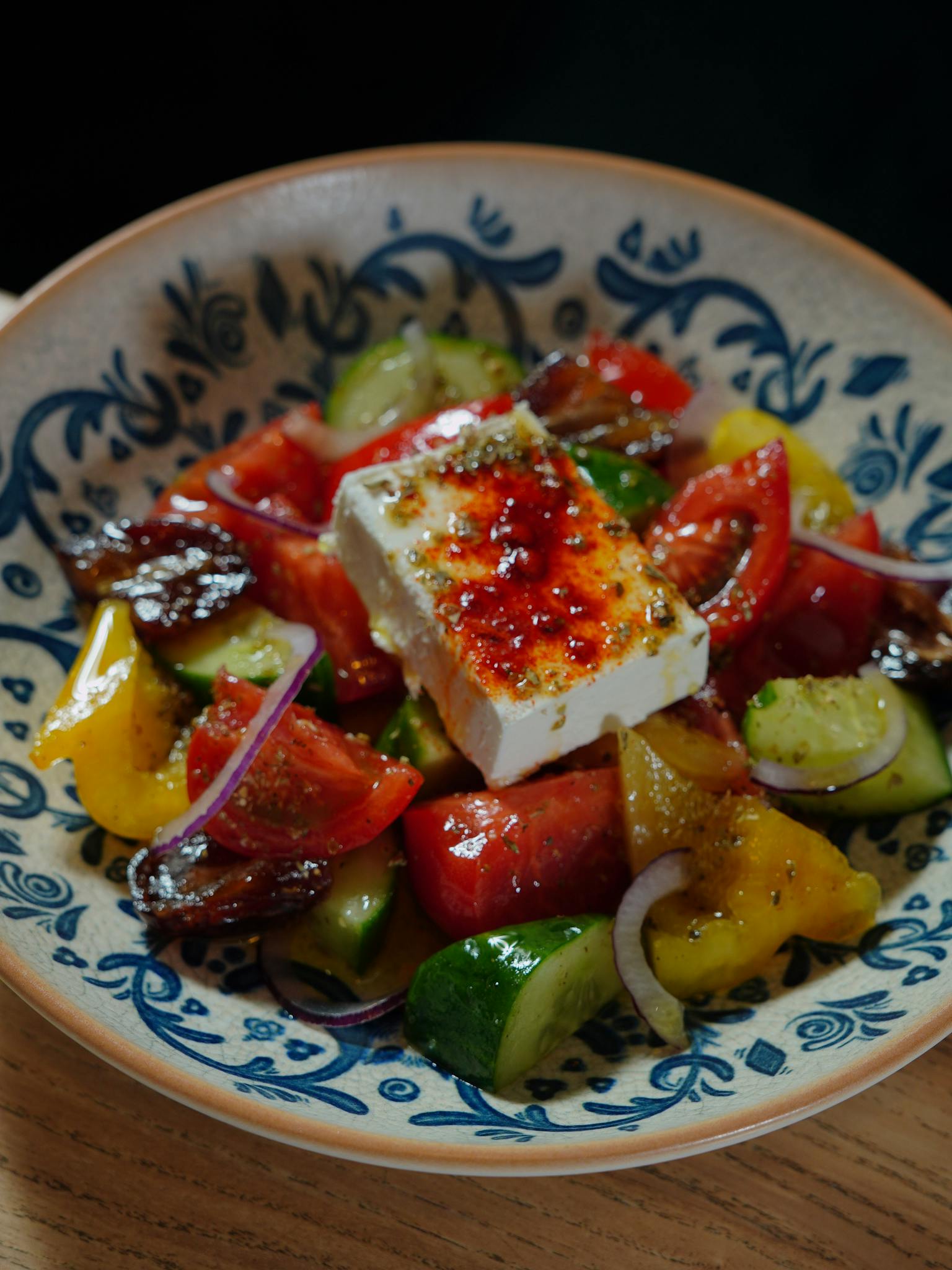 Delicious Greek salad featuring fresh vegetables and feta cheese in a decorative bowl.